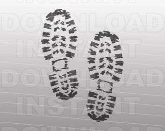 May include: Two black boot prints on a grey background. The prints are detailed with a tread pattern.