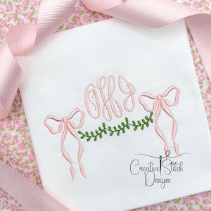 May include: White embroidered handkerchief with pink bows and a green garland. The handkerchief features the embroidered initials "OHJ" in pink. The words "Creative Stitch Designs" are written in black cursive.