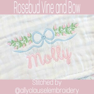 May include: Embroidered design featuring a light blue bow and a garland of pink rosebuds and green leaves. The name "Molly" is embroidered in pink script below the bow. The text "Rosebud Vine and Bow" is at the top.
