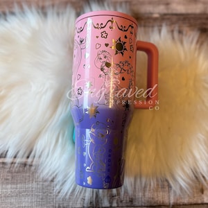 A colorful, patterned tumbler mug with a pink and purple design featuring characters from the Disney animated film Rapunzel.