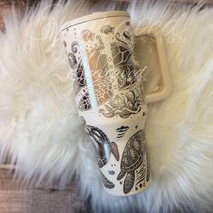 A white ceramic mug with a detailed, hand-painted design featuring various marine life and ocean-themed elements.