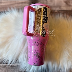 A pink and silver tumbler mug with a Disney-themed design, featuring a silhouette of a character and various Disney-related imagery.
