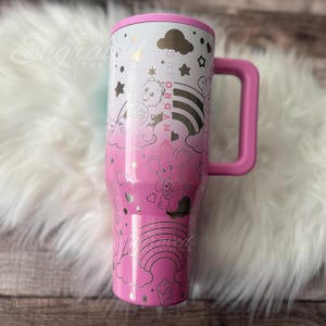 A pink and white tumbler mug with a handle, featuring a whimsical and playful design with stars, clouds, and other decorative elements.