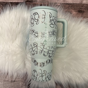 A turquoise insulated tumbler mug with a handle, placed on a white furry surface.