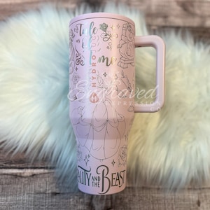 Puede incluir: Un vaso de color lila claro con asa, con dibujos lineales de personajes y citas de La Bella y la Bestia. El vaso tiene las palabras "Tale as Old as Time" y "Beauty and the Beast" impresas.