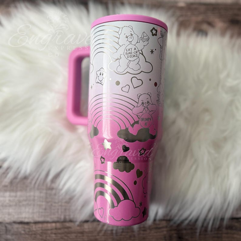 A pink and white tumbler mug with a whimsical design featuring a pink bear, clouds, rainbows, and stars.