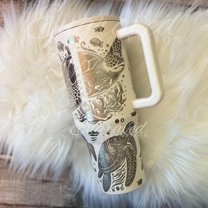 A white ceramic mug with a handle and a design featuring a turtle and other marine life.