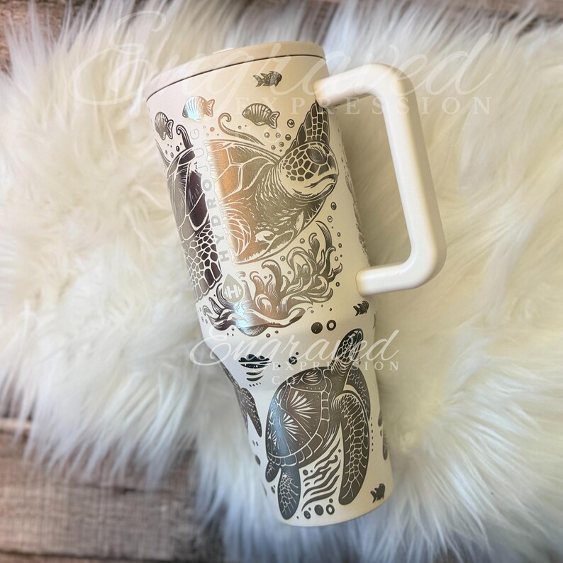 A white ceramic mug with a handle and a design featuring a turtle and other marine life.