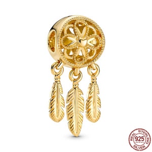 Puede incluir: Encanto dorado con un dise&ntilde;o detallado de atrapasue&ntilde;os con tres plumas colgantes. El encanto est&aacute; hecho de plata de ley y es parte de una colecci&oacute;n de joyas.