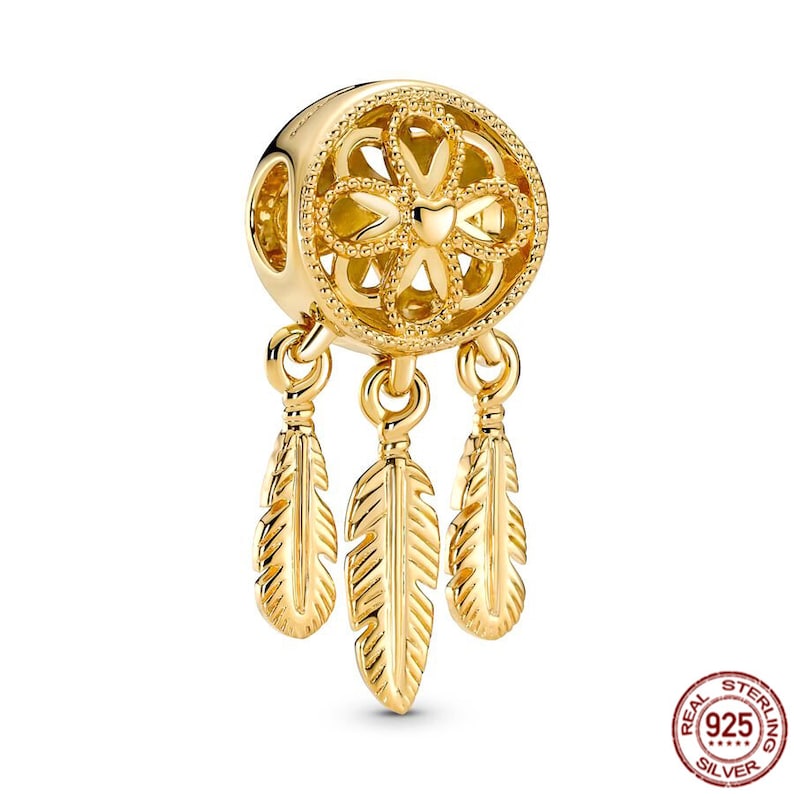 Puede incluir: Encanto dorado con un dise&ntilde;o detallado de atrapasue&ntilde;os con tres plumas colgantes. El encanto est&aacute; hecho de plata de ley y es parte de una colecci&oacute;n de joyas.