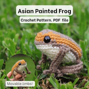 Puede incluir: Una rana pintada asiática de ganchillo con extremidades móviles. La rana tiene un vientre blanco, patas marrones y una cabeza con rayas naranjas y marrones. Incluye el texto "Asian Painted Frog" y "Crochet Pattern. PDF file."