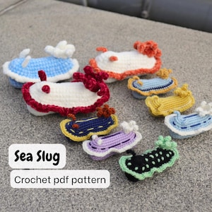 May include: A collection of colorful, crocheted sea slugs in various sizes and designs. The slugs feature a variety of colors, including blue, white, red, yellow, and purple. The text "Sea Slug" and "Crochet pdf pattern" are displayed on a white background.