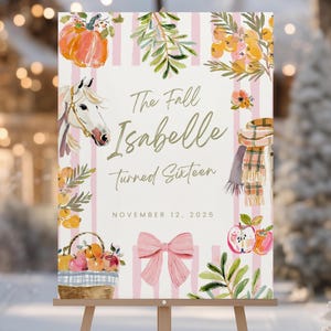 Puede incluir: Un letrero decorativo sobre un caballete de madera con el texto "The Fall Isabelle turned Sixteen" y "November 12, 2025". El letrero presenta ilustraciones de acuarela de una calabaza, un caballo, flores, una bufanda, manzanas y un lazo rosa, sobre un fondo a rayas rosas.