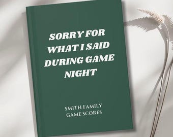 Puede incluir: Un diario verde oscuro con el texto "Lo siento por lo que dije durante la noche de juego" en blanco. La parte inferior del diario dice "Puntuaciones de juego de la familia Smith".