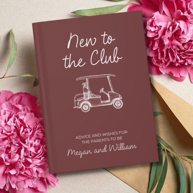 Op de afbeelding: Een bordeauxrood boek met de titel "New to the Club" en een golfkar-illustratie. Het boek bevat ook de tekst "Advice and Wishes for the Parents to Be" en de namen "Megan and William". Roze bloemen en bladeren omringen het boek.