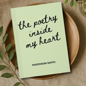 May include: A light green book titled "the poetry inside my heart" in black script. The author's name, Maddison Smith, is printed below the title. The book rests on a wooden plate.