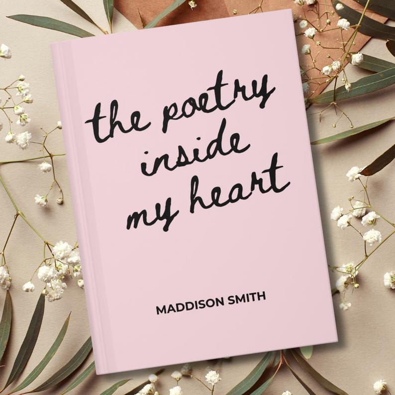 May include: A pink book with the title "the poetry inside my heart" in black cursive font. The author's name, Maddison Smith, is printed below the title. The book is surrounded by white flowers and green leaves.
