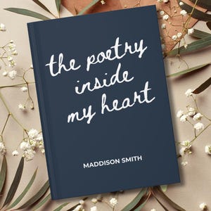 May include: A navy blue book with the title "the poetry inside my heart" in white script. The author's name, Maddison Smith, is printed below the title. The book is surrounded by white flowers and greenery.