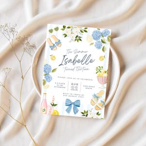 May include: A summer-themed invitation with the text "The Summer Isabelle Turned Thirteen." The design includes blue hydrangeas, lemons, and sandals. The invitation also includes the date August 22 and the time 3:00 PM.