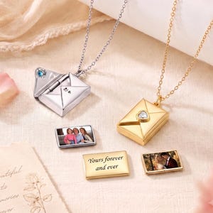 May include: Two envelope-shaped pendants on delicate chains, one silver-toned with a blue stone and one gold-toned with a heart-shaped stone. Each pendant opens to reveal a small rectangular photo insert. One metal insert is engraved with the text Yours forever and ever.