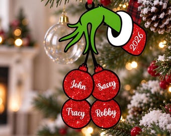 May include: A Christmas tree ornament featuring a green hand with a white cuff holding four red glittery circular baubles. The cuff displays the year 2026. Each red bauble is personalized with the white script names John, Sasey, Tracy, and Robby.