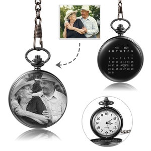 May include: Black pocket watch with a photo of an older couple on the front. The back of the watch has a calendar for May 2021 with a heart over the 19th.
