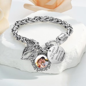 Może przedstawiać: Srebrna bransoletka z zawieszką, na której napisano "Będę trzymał cię w swoim sercu, dopóki nie będę mógł trzymać cię w Niebie". Zawieszka ma również małą ramkę na zdjęcie z fotografią pary.