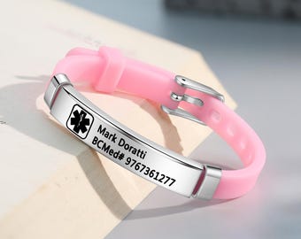 May include: Pink silicone medical alert bracelet with a silver plate engraved with the text "Mark Doratti BCMed# 9767361277" and a medical symbol.