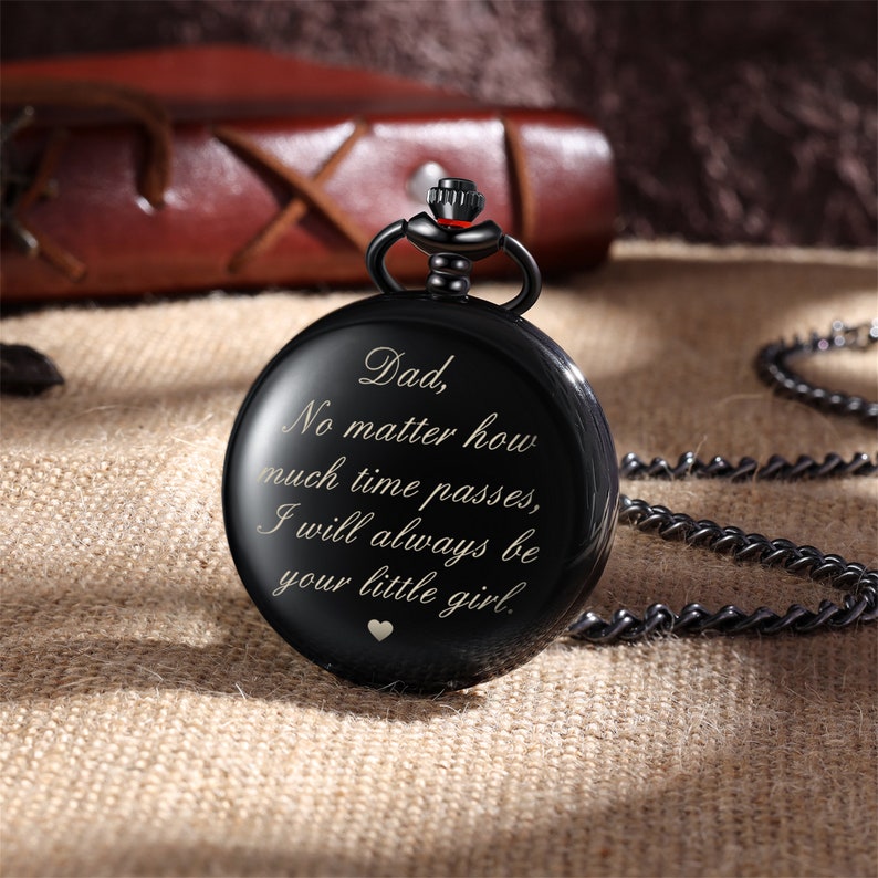 May include: Black pocket watch with a silver chain. The watch face has an inscription that reads: "Dad, No matter how much time passes, I will always be your little girl."