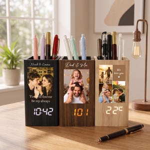 May include: Three rectangular wooden pen holders with integrated digital clocks. Each holder features a custom photo print, personalised text, and a top compartment for pens. The clocks display time or temperature in white or orange digital numerals.