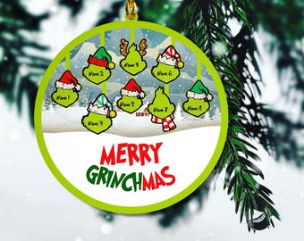 May include: A round green and white Christmas ornament with a snowy scene and eight Grinch characters. The ornament says "Merry Grinchmas".