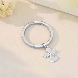 Peut inclure: Porte-cl&eacute;s en argent avec un ange grav&eacute; au dos du nom Daine. Le porte-cl&eacute;s est attach&eacute; &agrave; un anneau de cl&eacute; en argent.