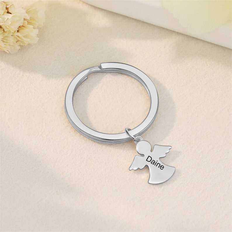 Peut inclure: Porte-cl&eacute;s en argent avec un ange grav&eacute; au dos du nom Daine. Le porte-cl&eacute;s est attach&eacute; &agrave; un anneau de cl&eacute; en argent.