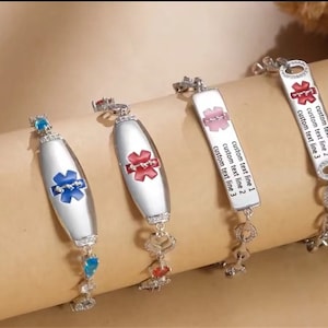 Puede incluir: Cuatro pulseras de alerta médica de plata con piedras de diferentes colores y un símbolo de estrella de la vida. Las pulseras tienen espacio para tres líneas de texto personalizado.  "custom text line 1", "custom text line 2", "custom text line 3"