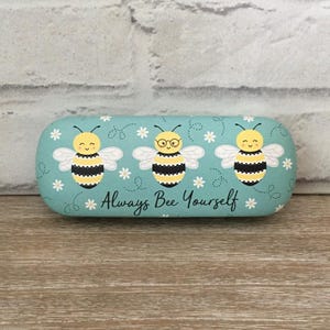 Może przedstawiać: Jasnoniebieskie etui na okulary z wzorem trzech kreskówkowych pszczół z tekstem "Always Bee Yourself".