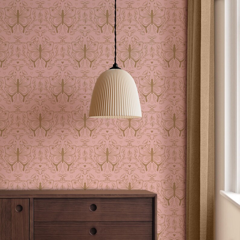 May include: A pale pink wallpaper featuring a gold butterfly design. A cream-coloured, ribbed pendant light hangs from the ceiling. A dark brown wooden dresser is visible at the bottom of the image.