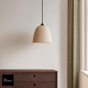 May include: A cream-coloured, ribbed pendant light hangs from a black cord. The light fitting has a rounded, bell-shaped design. The background includes a wooden cabinet, a green curtain, and a white wall.