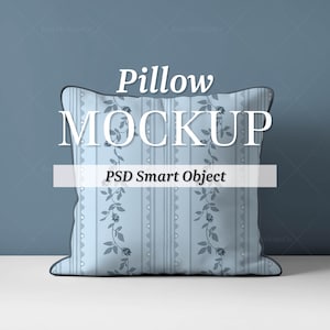 Peut inclure: Un coussin bleu clair avec un motif floral et le texte "Pillow MOCKUP PSD Smart Object". Le coussin a une bordure bleu foncé et est placé sur un fond bleu.