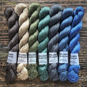 May include: Six skeins of yarn in various shades of brown, beige, green, teal, gray, and blue. Each skein is labeled with "90% Linen 10% Nylon" and the weight and yardage.
