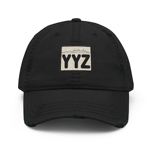 May include: Black distressed baseball cap with a white patch featuring a skyline and the text "YYZ" in black.