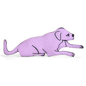 May include: A lavender-colored dog-shaped pillow with a repeating pattern. The dog is lying down with its front paws extended. Black outlines define the dog's features, including its ears, eyes, and tail.