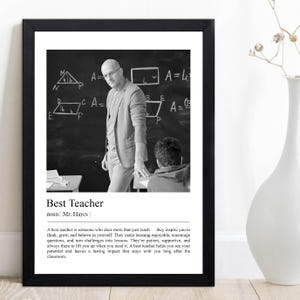 May include: Black and white framed print featuring a teacher in front of a chalkboard with geometric equations. The print includes the text "Best Teacher" and a definition. A white vase is in the background.