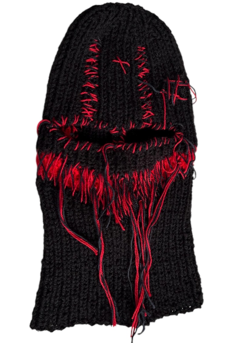 May include: Black knitted balaclava with red stitching and frayed edges. The balaclava has a hole for the eyes and nose.