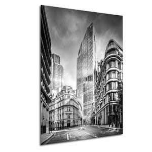 May include: A black and white photograph of a city street in London, England. The photo shows tall buildings, including the iconic skyscraper known as the "Walkie Talkie". The street is empty of people and vehicles, creating a sense of solitude.