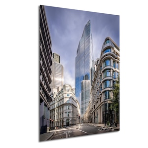 May include: A street scene in London, England, with tall modern buildings and older, traditional buildings. The street is empty, with a few cars parked on the side. The sky is cloudy and the sun is shining.