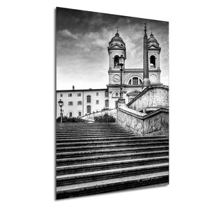 May include: Black and white photograph of a set of stairs leading up to a church with two bell towers. The stairs are made of stone and are very old. The church is in the background and is also made of stone.
