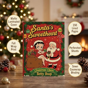 May include: A Christmas-themed book titled "Santa's Sweetheart" featuring Betty Boop and Santa Claus on the cover. The cover is red with green accents and includes the text "Christmas Cheer Betty Boop". The book has 150 lined pages and a sewn casewrap binding.