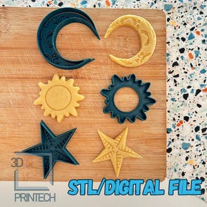 Pode incluir: Um conjunto de seis cortadores de biscoitos em forma de lua crescente, sol, estrela e anel. Os cortadores são feitos de plástico azul e amarelo e estão dispostos sobre uma superfície de madeira. STL/ARQUIVO DIGITAL.