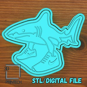 Könnte beinhalten: Ein hellblaues 3D-gedrucktes Haidesign mit Turnschuhen. Das Design enthält den Text "STL/DIGITAL FILE" und das Logo "3D PRINTECH". Der Hai hat eine detaillierte Kontur und ist vor einem Holzgrund platziert.