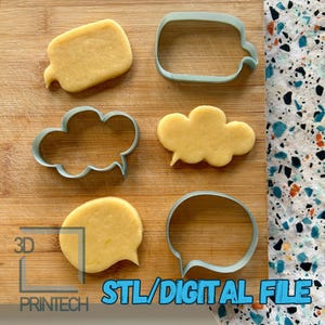 May include: Four cookie cutters in different shapes: a rectangle, a cloud, a speech bubble, and a rounded rectangle. The cookie cutters are made of blue plastic and are on a wooden surface. The cookie cutters are next to cookies that have been cut out with the cookie cutters.